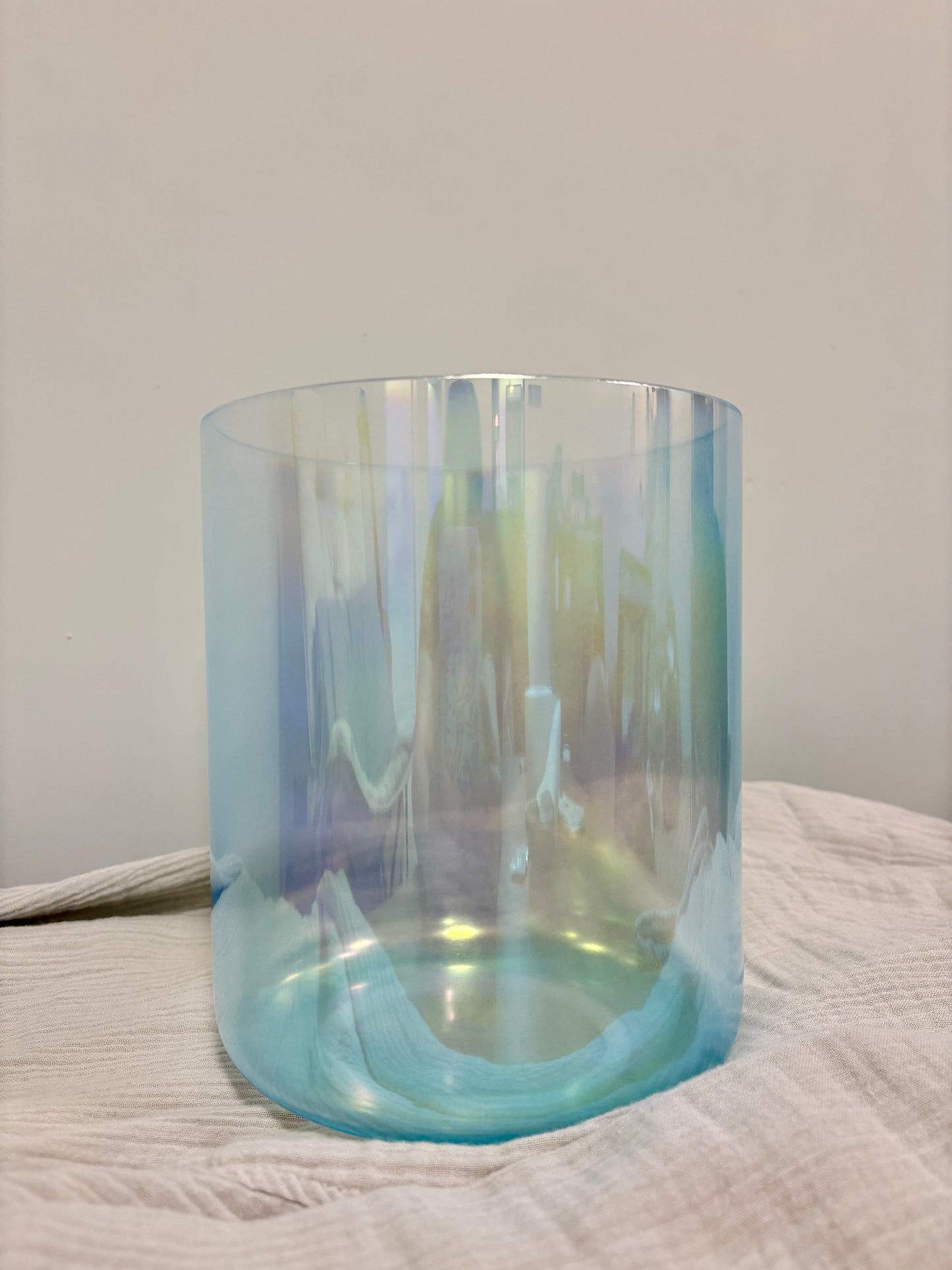 Blue gradient crystal singing bowl on a textured surface with a neutral background