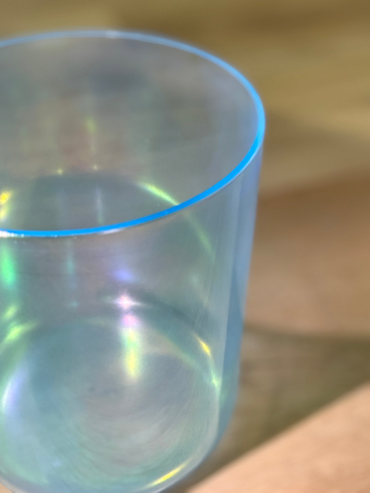 Blue gradient crystal singing bowl on a textured surface with a wooden background
